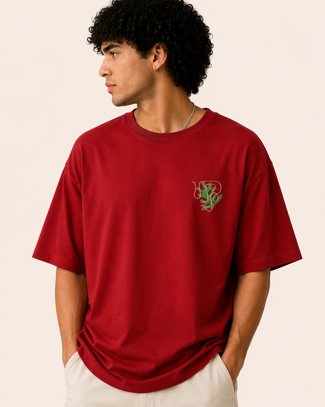 Person wearing a red t-shirt with a small logo on a beige background